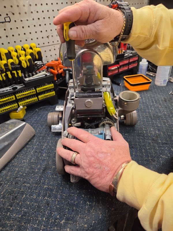 Vacuum cleaner repair technician working on an opened vacuum